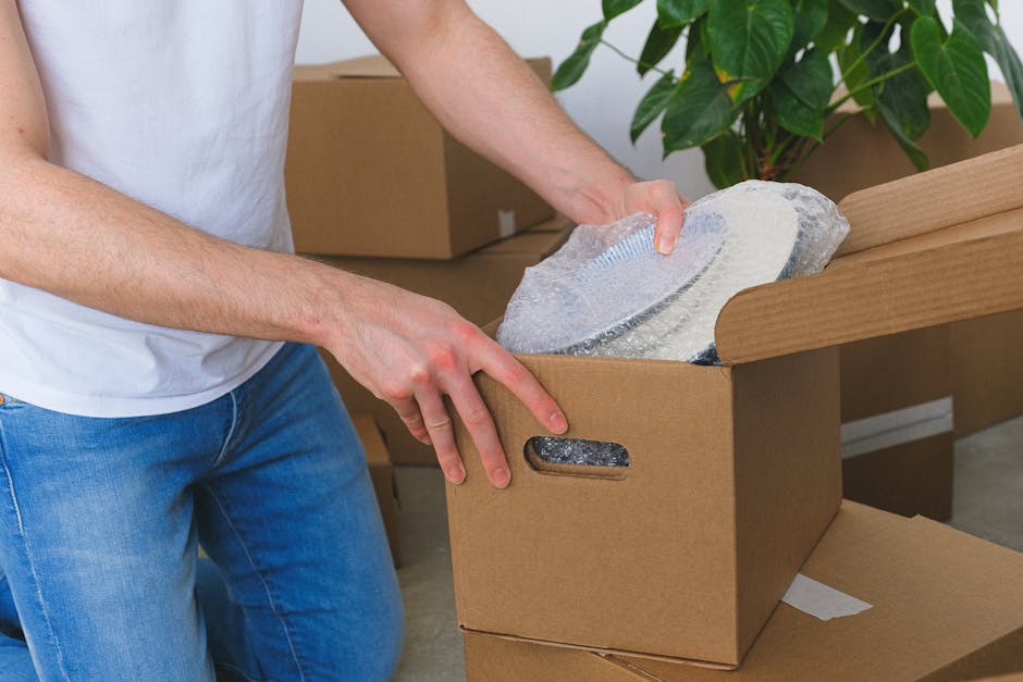 A person's hand holding a small pile of used disposable sanitary pads and tissues, with some of the pads wrapped in white and light blue plastic packaging, against a soft, cream-colored furry background. The image relates to waste disposal or personal hygiene care, which could be part of the packing and loading process during a home relocation or move. Man with Van Welling offers removals services that include the safe disposal of household waste, such as these items, during house moves or furniture transport. The scene highlights the importance of proper waste management and packing hygiene when preparing for a move, ensuring a clean and organized space inside the property or on the loading area outside.